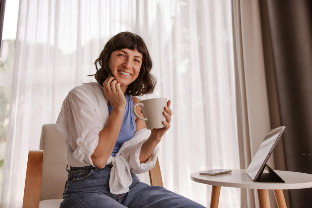 A woman smiling while holding a coffee
