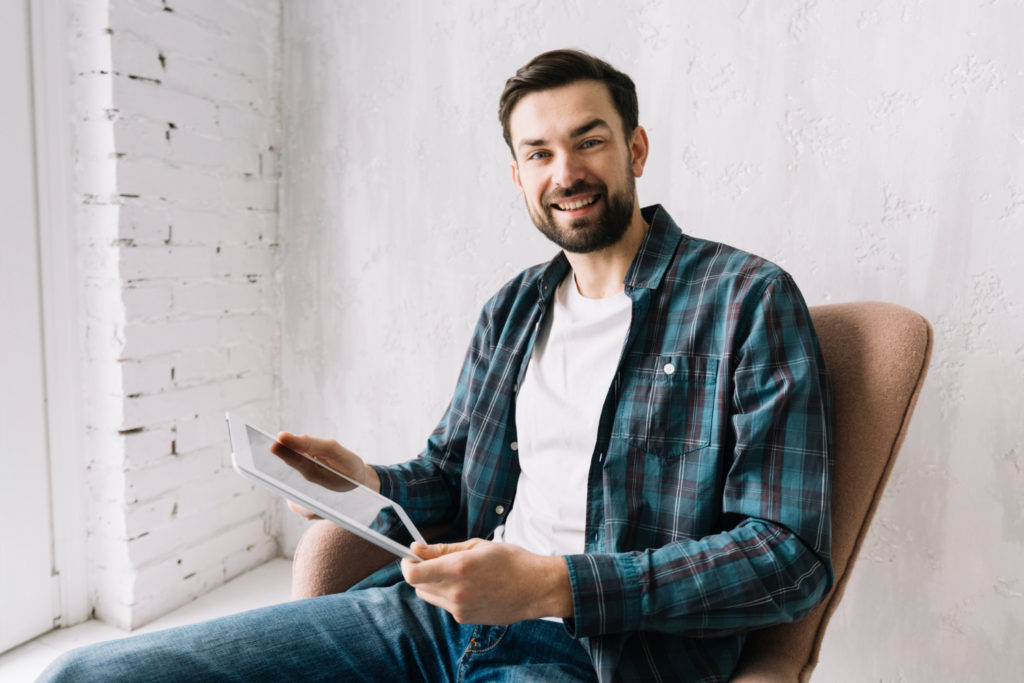 A man smiling while using a tablet